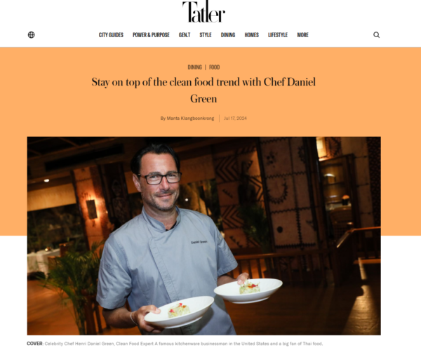 Chef holding two plated dishes in a restaurant setting.
